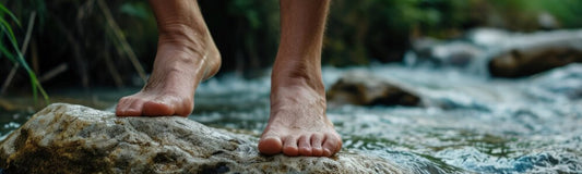 A person soaking their feet in warm water to soothe blisters, with ArmaSkin anti-blister socks beside them for added protection